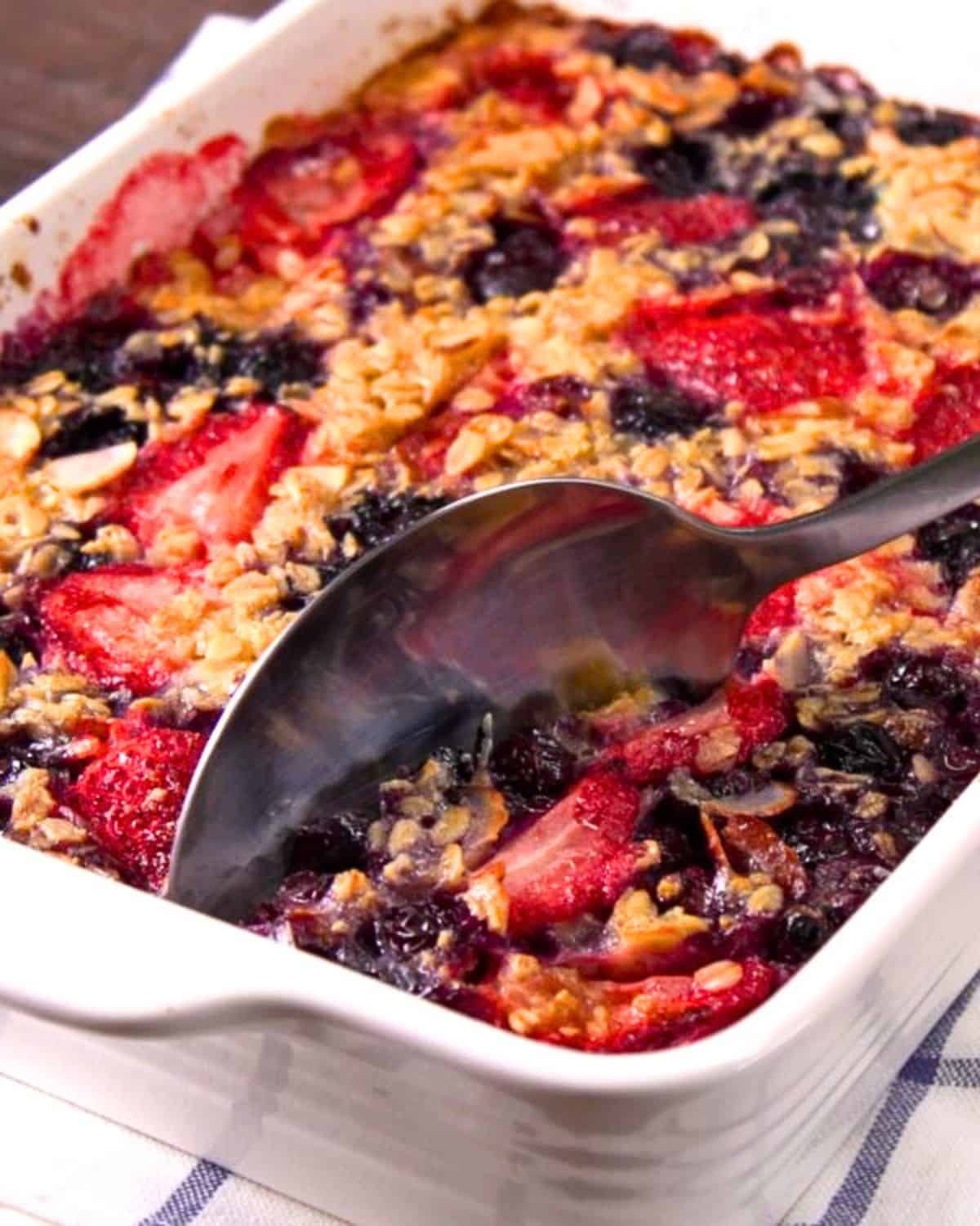 Baked oatmeal in casserole dish with serving spoon.