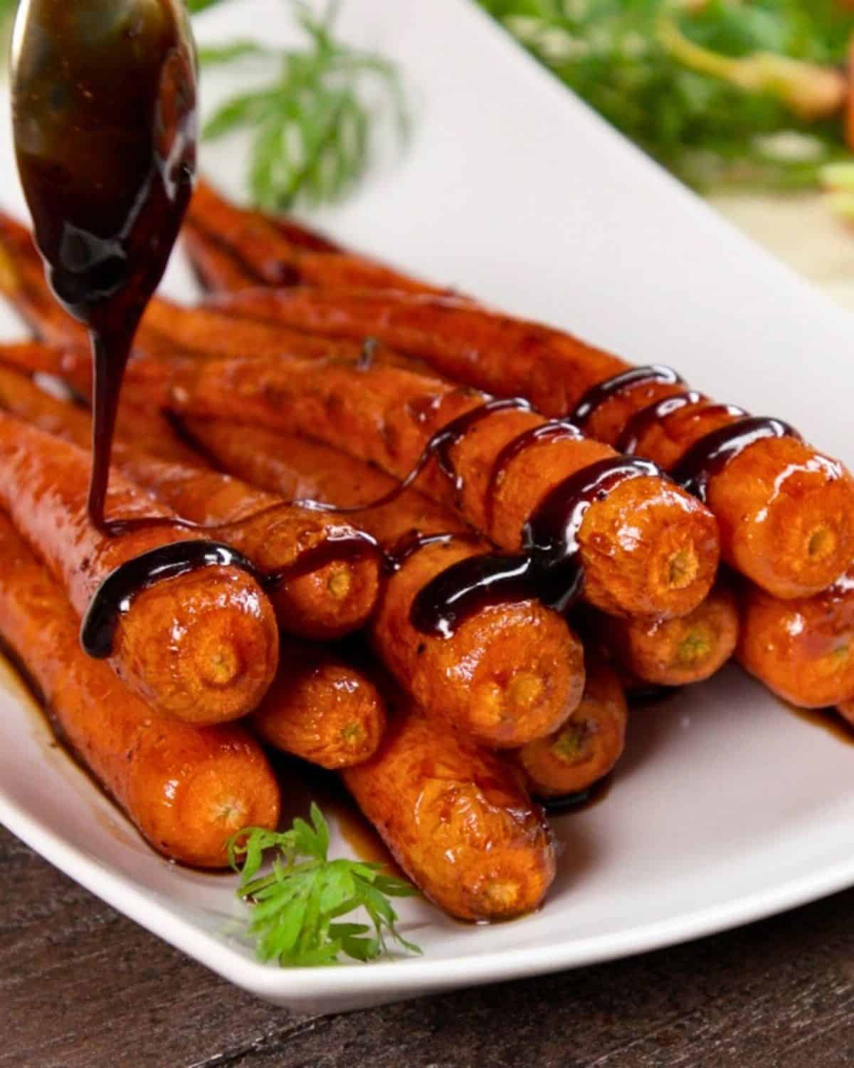 Roasted carrots with a dark honey-balsamic sauce on platter.