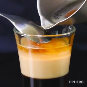 Pouring liquor over a spoon to create a layered B-52 shot.