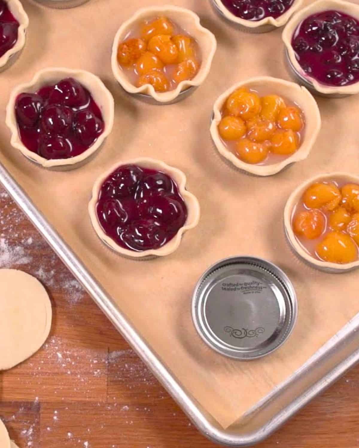 Pie filling in mason jar lids on baking sheet.