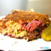 close up of reuben casserole on white plate with pickle.