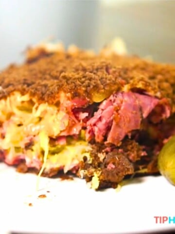 close up of reuben casserole on white plate with pickle.