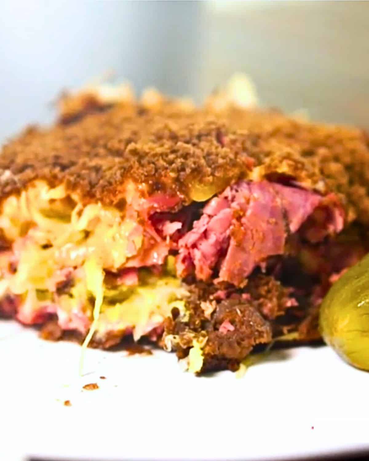close up of Reuben Casserole on white plate with pickle.