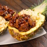 Teriyaki Chicken and pineapple rice in pineapple rind on white plate.